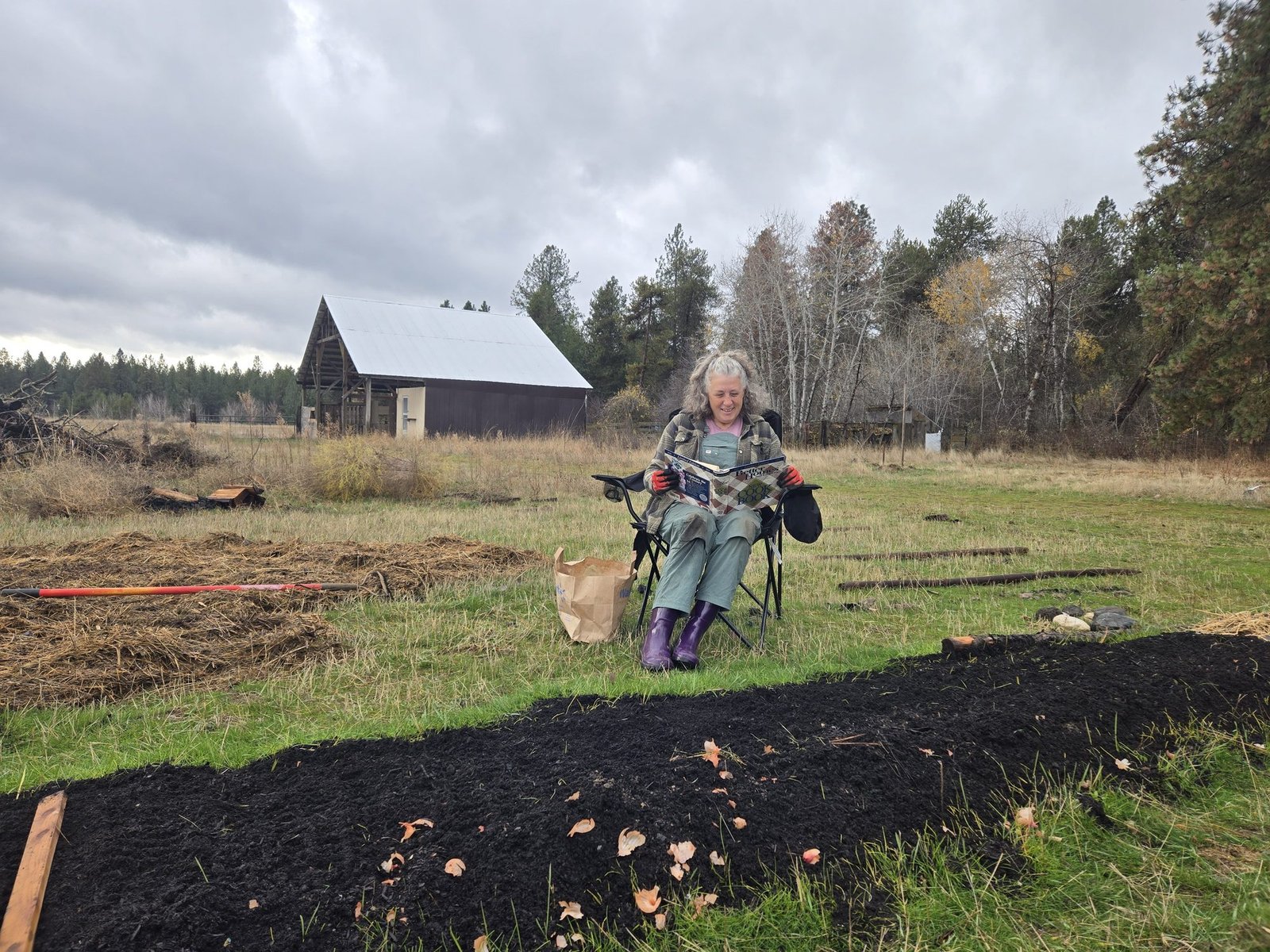 Tina reading a cookbook aloud to freshly planted garlic beds